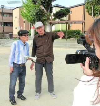 カメラの前で、荒川博之さん（中央）から震災当時の話を聞く三条杜夫さん（左）＝神戸市長田区本庄町２
