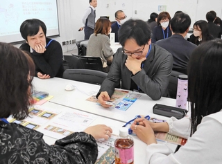 生理痛の疑似体験をする男性（右から２人目）。スイッチを入れると次第に複雑な表情を見せた＝神戸市中央区三宮町１