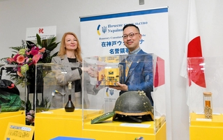 セレモニーで握手を交わすインナ・イリナさん（左）と岡部芳彦教授＝神戸市中央区港島１