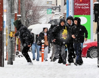 雪が積もる中、市街地を歩く高校生ら＝２６日午前、豊岡市若松町（撮影・大高碧）