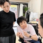 介助者の援助を受けて働く田中順子さん（中央）＝神戸市東灘区