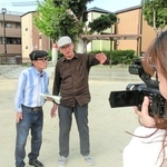カメラの前で、荒川博之さん（中央）から震災当時の話を聞く三条杜夫さん（左）＝神戸市長田区本庄町２