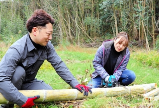 伐採した竹を竹筒の形に整える浜崎真乃さん（右）とＨＡＮＤＳの藤本真一さん＝神戸市須磨区多井畑