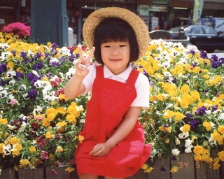 花壇に座り、はにかむ小西希ちゃん＝１９９４年５月３日、神戸市灘区（小西眞希子さん提供）