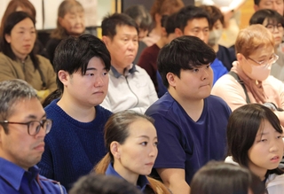 崔さん親子の話に耳を傾ける関西学院大の中村允信さん（中央左）と姜珉赫さん（同右）＝神戸市長田区二葉町５（撮影・吉田敦史）