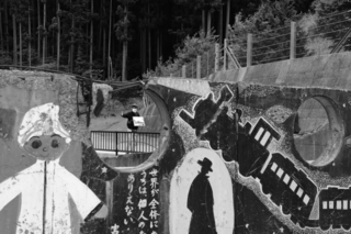 大川小学校で、子どもたちが描いた壁画と語り部の男性を撮影した１枚＝宮城県石巻市の同校（山崎エリナさん撮影）