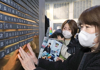 足田伸二さんの銘板に手を添える姉のるみ子さん（右）ら＝１６日午後、神戸市中央区加納町６、東遊園地（撮影・吉田敦史）