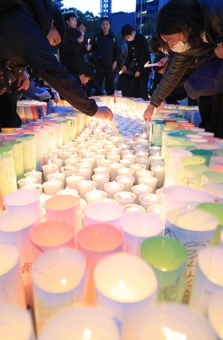 「１．１７」を翌日に控え、紙灯籠に明かりをともす市民ら＝１６日午後、神戸市中央区加納町６、東遊園地（撮影・丸山桃奈）