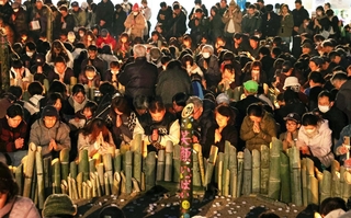 日が暮れた後、犠牲者を悼んで黙とうする人たち。それぞれの記憶をつないでいく＝１７日午後５時４６分、神戸市中央区加納町６、東遊園地（撮影・笠原次郎）