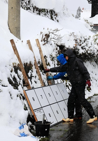 雪の中、衆院選のポスター掲示板を設置する業者の男性＝21日午後、兵庫県新温泉町岸田（撮影・長谷部崇）