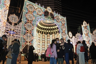 神戸ルミナリエの「スパッリエーラ」の前で写真を撮る人たち＝３０日夜、神戸市中央区加納町６、東遊園地（撮影・丸山桃奈）