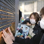 足田伸二さんの銘板に手を添える姉のるみ子さん（右）ら＝１６日午後、神戸市中央区加納町６、東遊園地（撮影・吉田敦史）