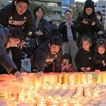 「つむぐ」の文字に並べた紙灯籠に火をともすコベルコ神戸スティーラーズの日和佐篤（手前中央）ら＝神戸市中央区加納町６（撮影・丸山桃奈）