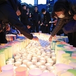 「１．１７」を翌日に控え、紙灯籠に明かりをともす市民ら＝１６日午後、神戸市中央区加納町６、東遊園地（撮影・丸山桃奈）