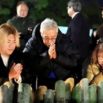 手を合わせる向邦男さん（中央）と妻千鶴さん（右）、孫の池田睦さん＝１７日午前６時１９分、神戸市中央区加納町６、東遊園地（撮影・中西幸大）