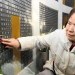 震災で犠牲になった長女津村美保さんと孫の有香ちゃんの名前が記された銘板に触れる森本律子さん＝１月１７日午前１０時４分、神戸市中央区加納町６、東遊園地