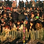 日が暮れた後、犠牲者を悼んで黙とうする人たち。それぞれの記憶をつないでいく＝１７日午後５時４６分、神戸市中央区加納町６、東遊園地（撮影・笠原次郎）