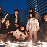 犠牲者を追悼する催しで、子どもが手にしたろうそくの火を見つめる人たち＝１７日午後５時４１分、神戸市長田区若松町４、ＪＲ新長田駅前（撮影・風斗雅博）