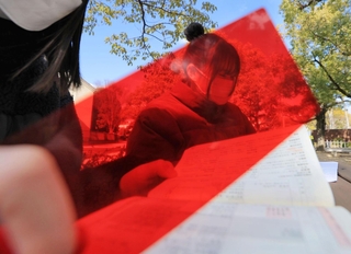 入試会場で、単語帳と赤いシートを手に次の科目に備える受験生＝西宮市上ケ原一番町、関西学院大