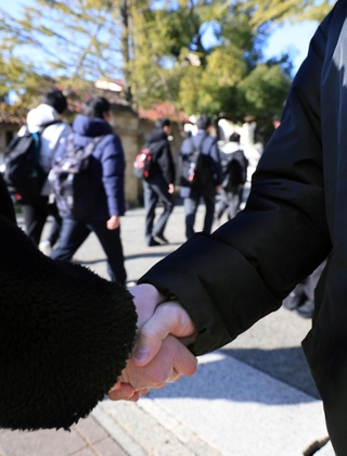 受験会場へ入る高校生と、応援に駆けつけた高校教諭ががっちり握手＝西宮市上ケ原一番町、関西学院大学（撮影・吉田敦史）