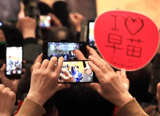 自民党総裁の高市早苗首相を捉えるスマホと「Ｉ♡早苗」のうちわ＝西宮市内