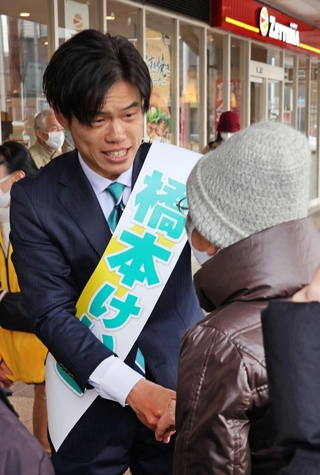 有権者と握手する橋本慧悟氏。今回の選挙戦では、泉房穂氏の「一番弟子」というアピールは控えめだった＝明石市内
