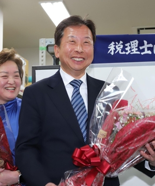 花束を手に笑顔を見せる大串正樹氏＝川西市小花１（撮影・小林良多）