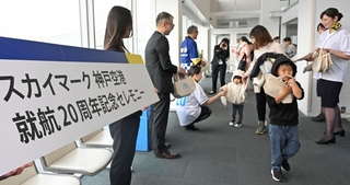 乗客に就航２０年の記念品を配るスカイマークのスタッフら＝１６日午前、神戸市中央区、神戸空港（撮影・大田将之）