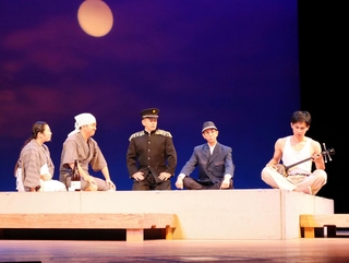 演劇「島守のうた」では、島田叡（右から２人目）が村の宴に足を運び県民に溶け込むシーンが演じられ、明るい人柄を表現した＝神戸文化ホール