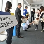 乗客に就航２０年の記念品を配るスカイマークのスタッフら＝１６日午前、神戸市中央区、神戸空港（撮影・大田将之）