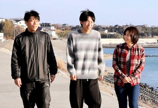 震災後にできた防潮堤の上を、次男建介さん（中央）、夫剛さん（左）と歩く高橋和恵さん＝宮城県南三陸町歌津