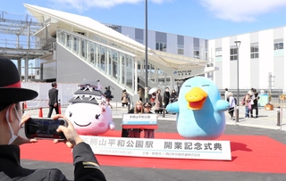 駅員の制服を着てマスコットと記念撮影する子どもら＝１４日午前、ＪＲ手柄山平和公園駅