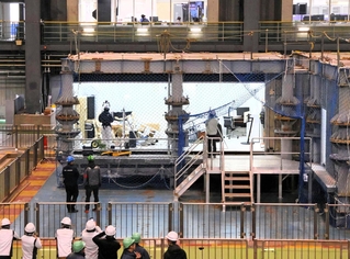 巨大地震の揺れを再現した実験で、居住空間の被害を確認する関係者ら＝三木市志染町