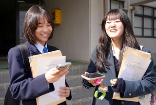 スマートフォンで合否を確認して、喜ぶ生徒ら＝１９日午後、神戸市長田区寺池町１、兵庫高校