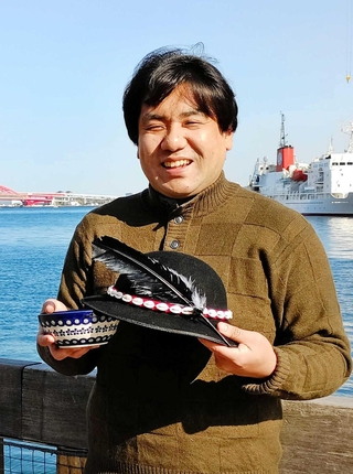 ポーランドの民族衣装の帽子を手に、同国と日本の絆について話す岡﨑拓さん＝神戸市中央区東川崎町１