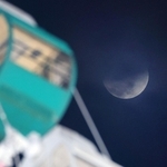 部分食の後半に差しかかった月。左は淡路サービスエリアの大観覧車＝３日午後９時４２分、淡路市岩屋から（撮影・吉田敦史）