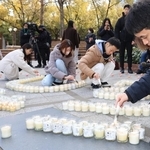 東日本大震災の被災地に思いをはせ、キャンドルに火を付ける人たち＝１１日午後、神戸市中央区加納町６、東遊園地（撮影・吉田敦史）