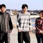 震災後にできた防潮堤の上を、次男建介さん（中央）、夫剛さん（左）と歩く高橋和恵さん＝宮城県南三陸町歌津