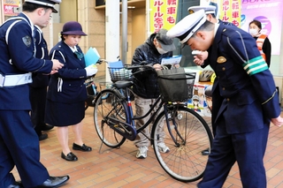 青切符の制度開始に合わせて自転車利用者に啓発チラシを手渡す生田署員ら＝１日午前、神戸市中央区元町通１