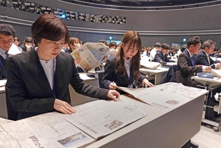 朝刊紙面を広げ、研修に取り組む新人職員ら＝神戸市東灘区向洋町中６