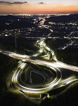 東・北播磨地域をつなぐ東播磨道の小野ランプ。夕暮れに、光の道が浮かび上がった＝小野市池尻町（ドローンで撮影）
