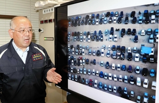 車中泊避難者の車で埋まったグラウンドの写真を前に熊本地震を振り返る吉永浩伸さん＝熊本市中央区手取本町