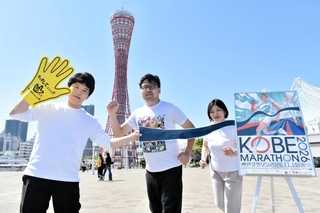 ポスターにちなんだポーズでランナー募集開始をＰＲする神戸マラソン実行委員会事務局の職員＝神戸市中央区波止場町