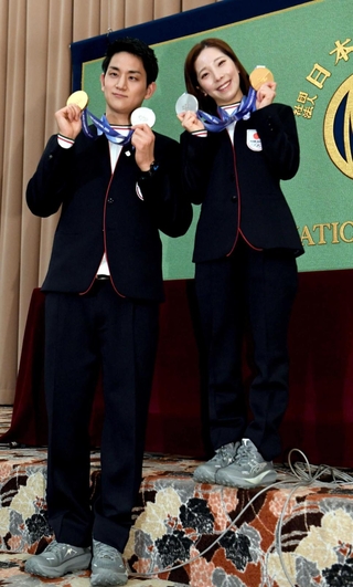 ミラノ・コルティナ冬季五輪で獲得したメダルを両手に笑顔を見せる木原龍一（左）と三浦璃来＝２月２５日、日本記者クラブ