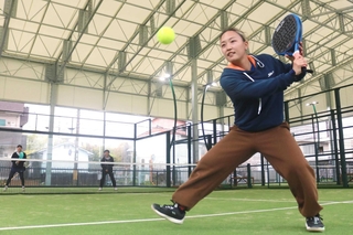 ガラスに跳ね返ったボールを打ち返す沓名舞子さん＝尼崎市南城内、パデル道場