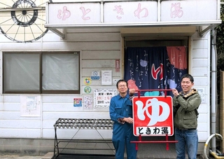 修復した看板を手渡す志方功一さん（右）と受け取る鹿嶋克弘さん（左）＝神戸市東灘区御影本町８、ときわ湯（志方功一さん提供）