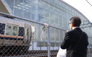 事故現場のフェンスに献花し、手を合わせる男性＝２５日午前７時４７分、尼崎市久々知３（撮影・吉田敦史）