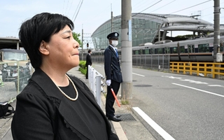 現場周辺で電車を見つめ、唇をかみしめる原口佳代さん。夫浩志さんを事故で失った＝２５日午前、尼崎市久々知西町２（撮影・斎藤雅志）