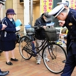 青切符の制度開始に合わせて自転車利用者に啓発チラシを手渡す生田署員ら＝１日午前、神戸市中央区元町通１