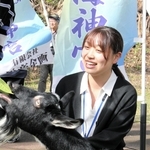 ヤギと戯れる子どもらを見守る名桜大学の小溝亜美さん＝沖縄県本部町